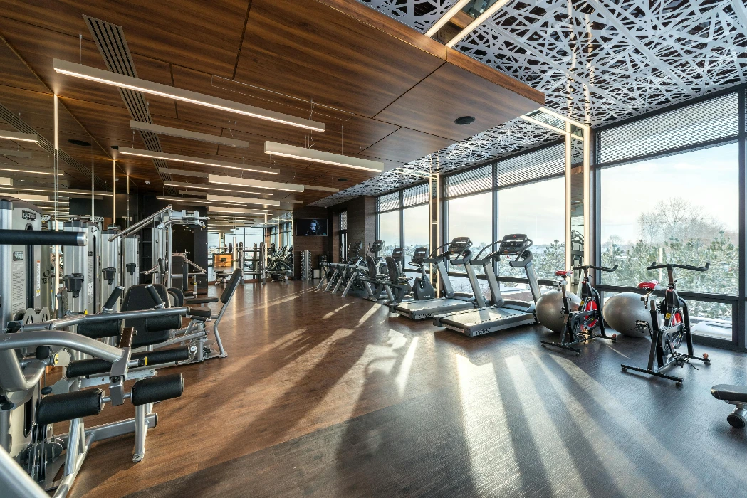 Spacious modern gym with treadmills, exercise bikes, and weights under natural lighting.